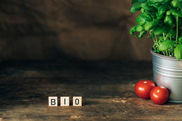 深色木制背景上有字母，一盆新鲜的罗勒和番茄。图片下载