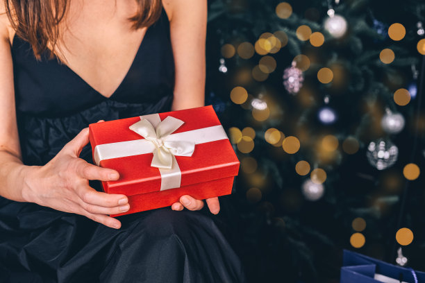 冬季销售。一名年轻女子在圣诞树下打开新年或圣诞节的礼品盒图片下载
