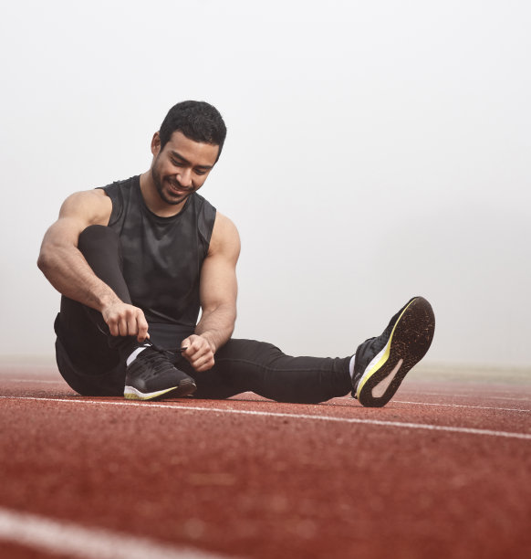 一名年轻男性运动员在比赛前系鞋带图片下载