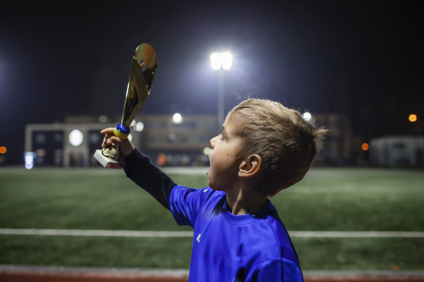 年轻的足球运动员，身穿十号蓝色球衣，在进致胜球后手持优胜者杯图片下载