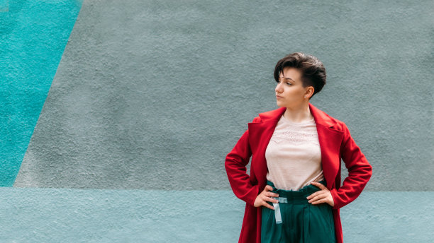 偷拍肖像年轻的黑发女人短头发在蓝色的墙背景。户外写真现代z一代红衣女子图片下载