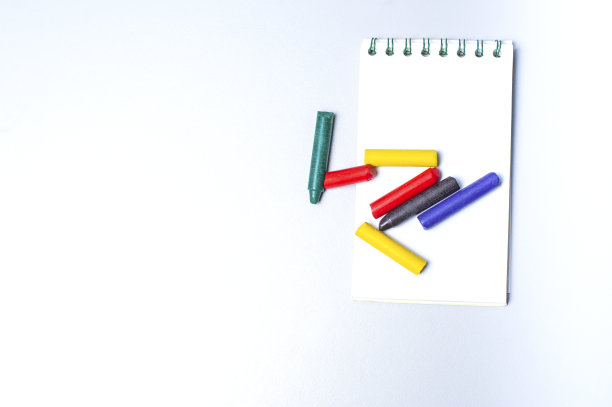 笔记本和木制彩色笔隔离在白色背景上。本空间图片下载