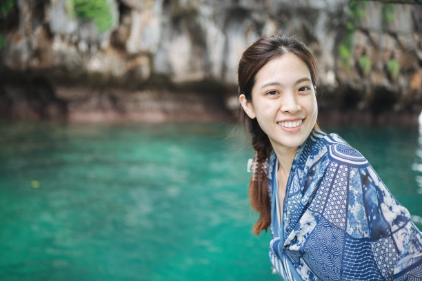 微笑的亚洲人享受旅游在清晨的海滩上欣赏长尾船翡翠洞穴(Tam Morakot)在泰国南部度假图片下载