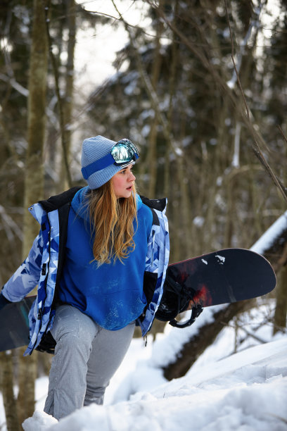 图片是一名女单板滑雪运动员的肖像，她戴着一个头盔，在眼镜中有一个明亮的反射。以高高的雪山为背景图片下载