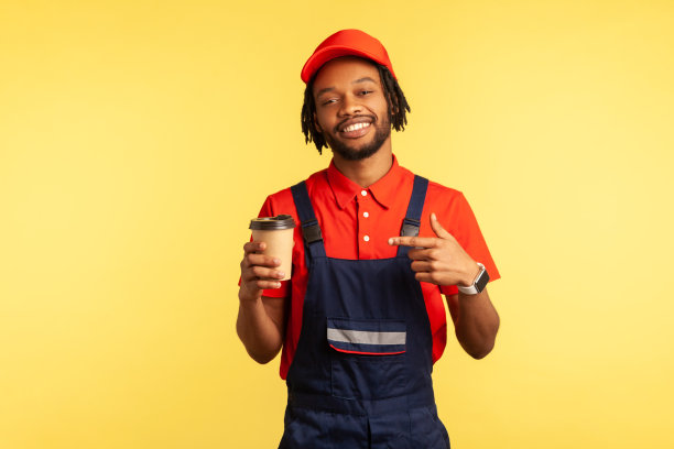 穿着蓝制服的勤杂工用手指着一次性咖啡杯，享受着热饮。图片下载