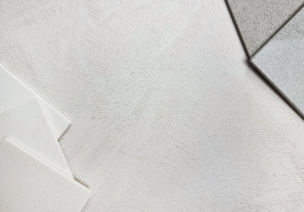 粒状灰色人造石，白色石英石样本样本放置在灰色石膏水泥层压背景(集中在中心)。室内材料元素的颜色匹配。图片下载
