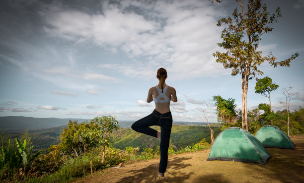 年轻女子在山上练习瑜伽度假野营图片下载