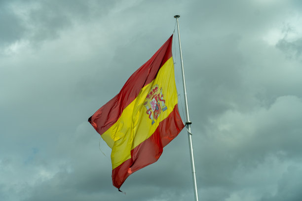 西班牙国旗在风中与黑暗风暴云在背景的观点图片下载