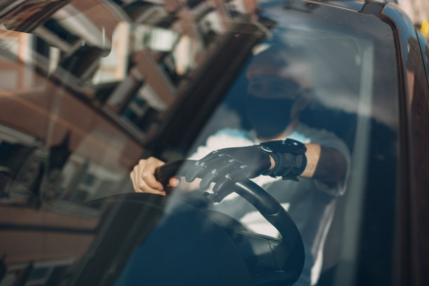 年轻的残疾人司机用人工假肢手驾驶汽车。图片下载