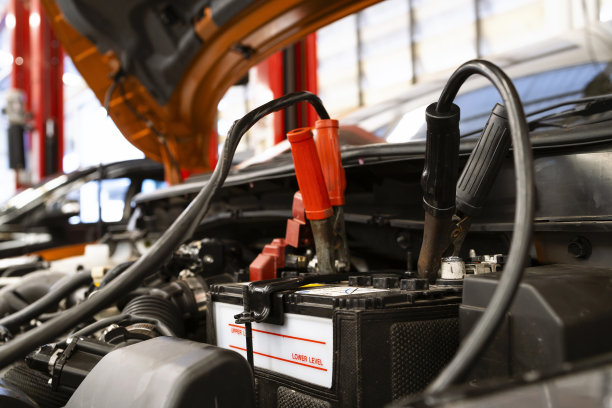 汽车维修的概念。特写镜头通过跨接电缆为汽车电池充电，背景是软聚焦和过光图片下载