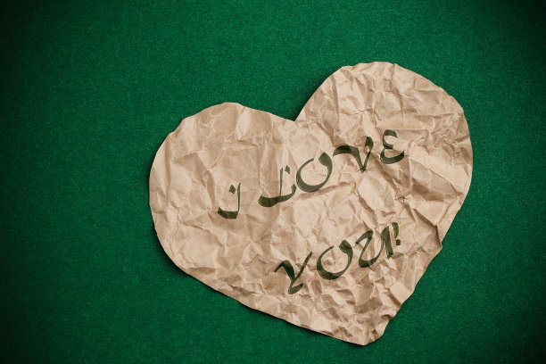 皱巴巴的心在绿色背景和小插图。心里刻着“我爱你”。图片下载