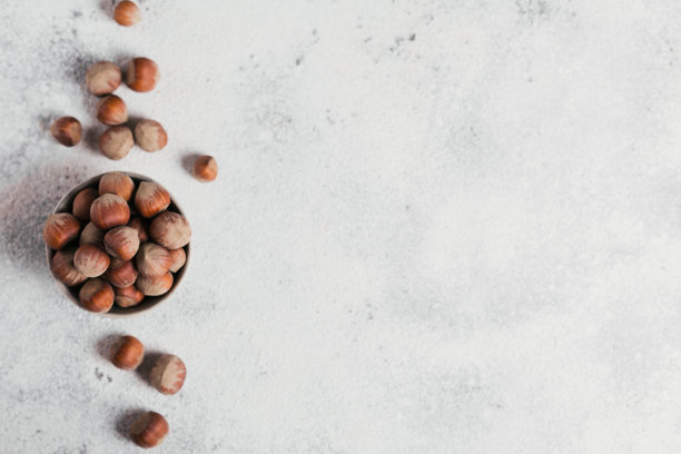 一堆榛子榛子放在碗里，背景是白色的。带壳的新鲜坚果。图片下载