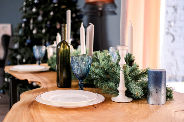 白色盘子、酒杯、蜡烛和杉木树枝做的装饰品。与家人和朋友一起吃圣诞或新年大餐的节日餐桌。图片下载