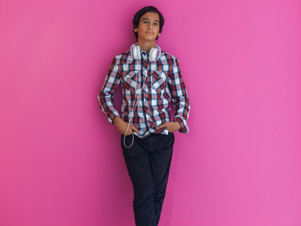 阿拉伯少年戴着耳机听音乐粉红色背景图片下载