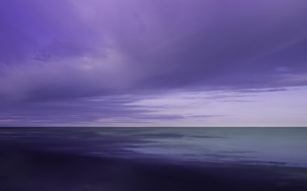 戏剧性的云景与紫色，粉红色和蓝色的风暴云聚集在蓝色的海水。图片下载