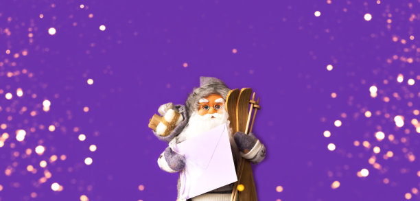 圣诞老人穿着灰色毛衣，手里拿着字母，背景是紫色的。圣诞贺卡或节日装饰。空间创意副本。图片下载