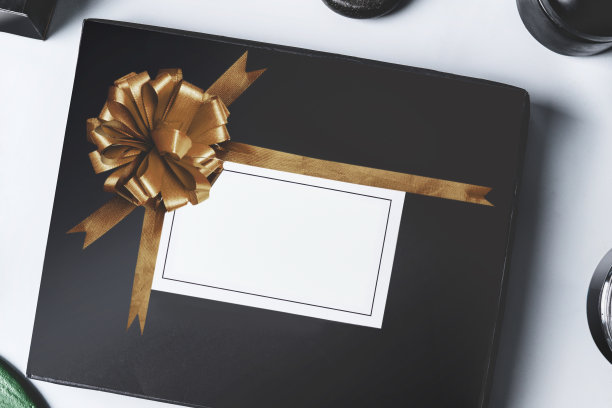 黑色美容盒与金色丝带和空白的白色品牌模拟在浅色背景，俯视图。图片下载