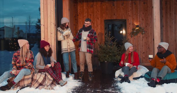 新年假期放假。一群快乐的朋友在温馨的圣诞树屋阳台边喝茶聊天，慢动作。图片下载