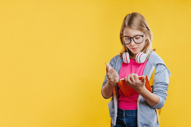 快乐的少女拿着背包阅读书在黄色的背景图片下载