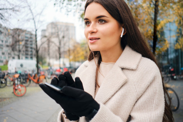 迷人的女商人穿着大衣在城市街道上笨拙地使用手机图片下载