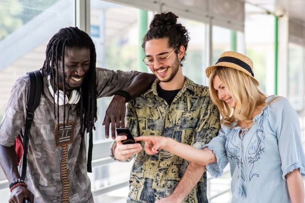 快乐的一群朋友在机场或车站旅行和步行，多民族的人享受旅行，看智能手机搜索和方向，游客使用技术为他们的旅行图片下载