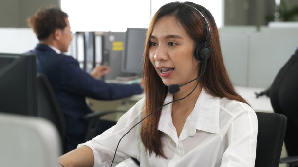 呼叫中心年轻员工戴着耳机工作，面带微笑的客服客服团队在工作中包围图片下载