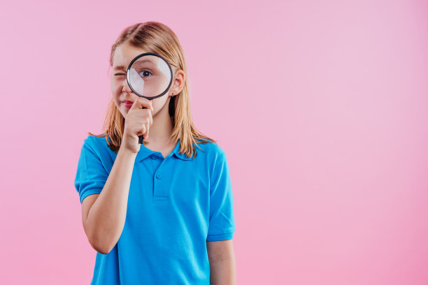 女学生看扔放大镜在粉红色的背景图片下载