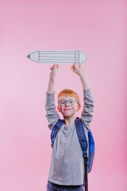 小女孩拿着纸素描铅笔在粉红色的背景图片下载