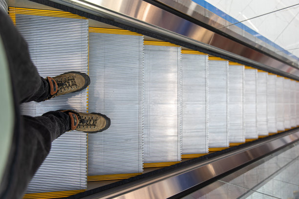 男人的脚在自动扶梯上，俯视图。图片下载