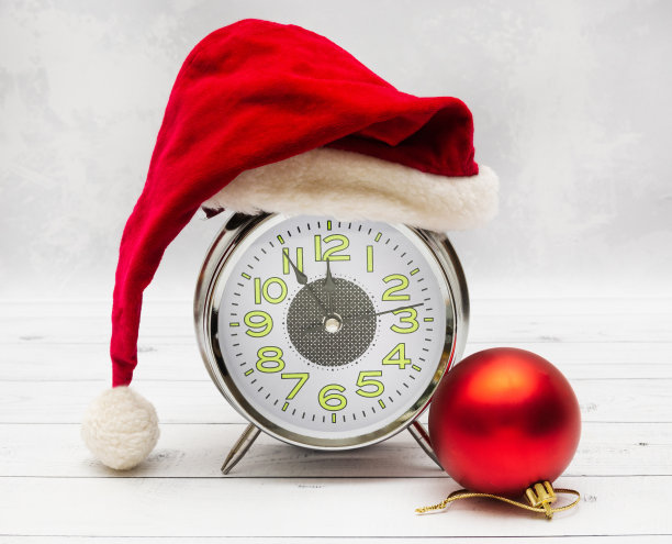 新年或圣诞卡:闹钟在圣诞老人的帽子和红色的球。圣诞节和新年的概念图片下载