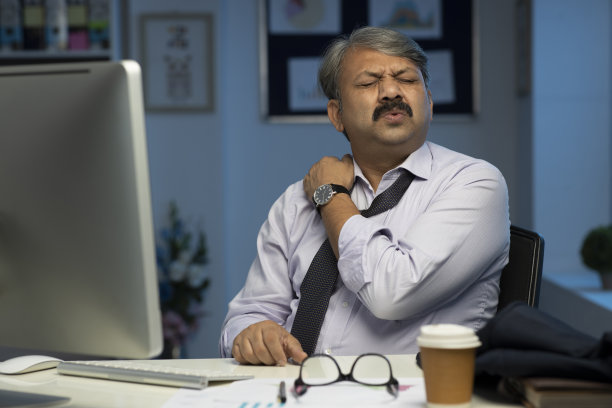 穿着正装的商人坐在办公室照片中按摩肩膀图片下载