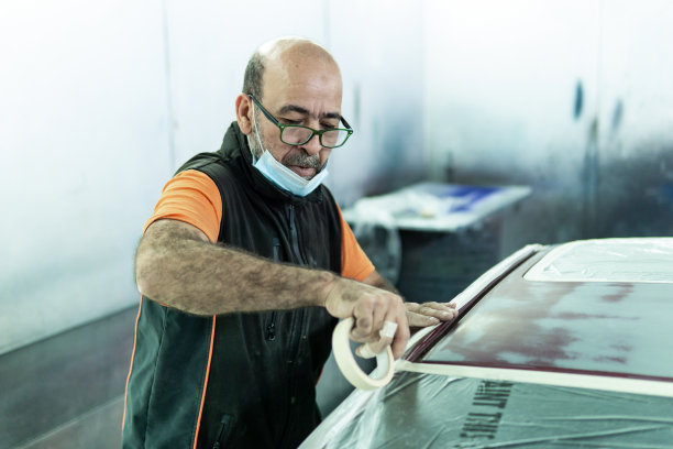 汽车修理工在车库里修理汽车准备喷漆。在车间里保护汽车的边缘图片下载