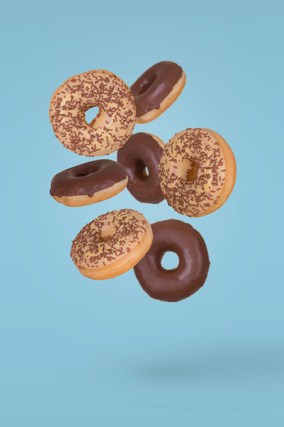 甜甜圈顶部有白巧克力和黑巧克力，并在蓝色的背景上洒上巧克力屑。图片下载