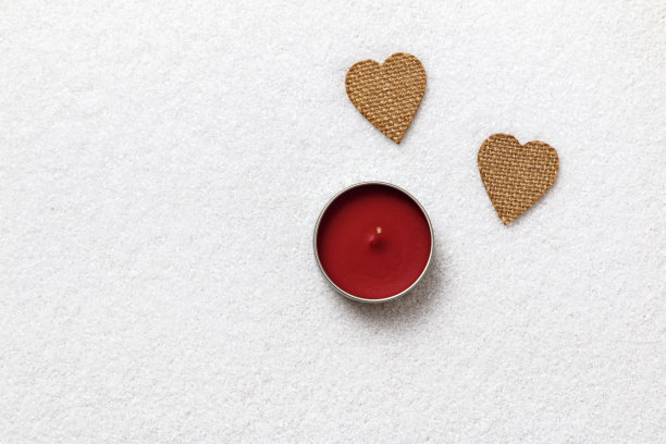 情人节。雪白的雪地上有两颗心和一支蜡烛。图片下载