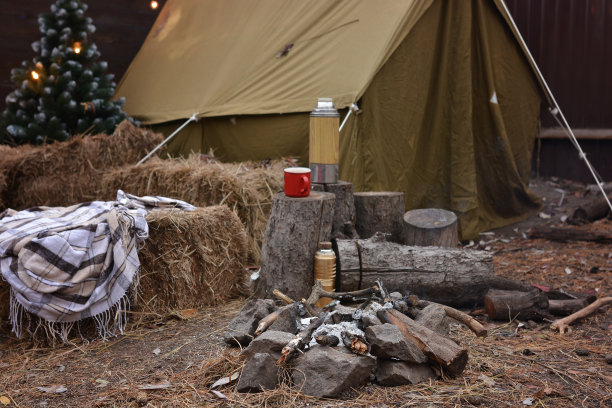游客帐篷，圣诞树，柴火，保温瓶，杯子，室外花环灯的木制背景。在徒步旅行、敌对行动、旅游、登山期间庆祝圣诞节图片下载