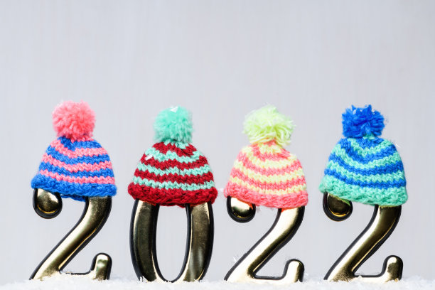黄金数字2022与多色针织帽子在白色的背景与雪。新年的背景是2022年图片下载