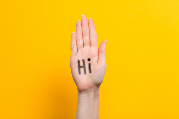 世界你好。女性举起手，手掌上写着“嗨”。黄色背景。本空间图片下载