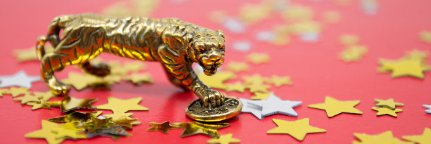 一个铜像的老虎与硬币-象征中国新年2022在一个红色的背景，金色和银色的星星，复制空间图片下载