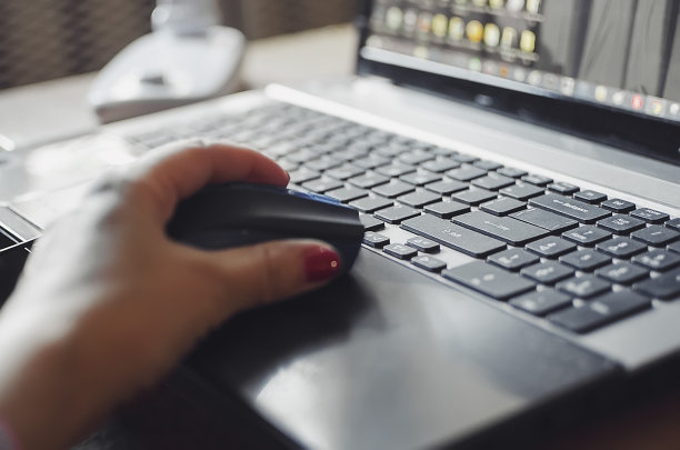 一名妇女在电脑前工作，手拿着电脑鼠标的特写。在家远程工作。图片下载