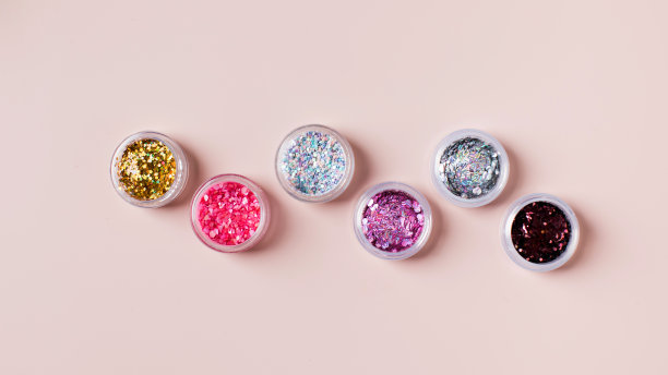 闪亮的闪光粉为节日的美甲圣诞派对在粉红色的背景图片下载