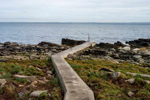 有混凝土码头的多岩石的海岸线。蓝色的水和蓝色的天空在背景中。图片来自瑞典Skalderviken图片下载