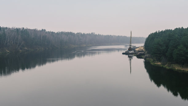 河上漂浮着起重机。在岸边附近作业的挖泥起重机。保护河流流。自然，河流，天空，云彩。图片下载