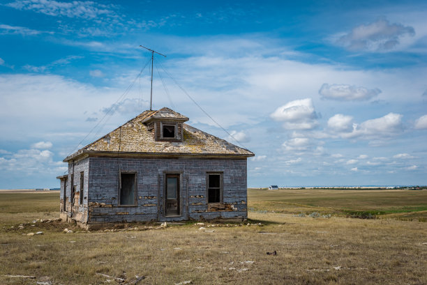 萨斯喀彻温大草原上的一座废弃房屋，背景是一座历史悠久的教堂图片下载