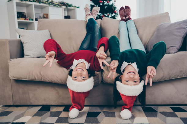 照片的两个积极的时髦的孩子躺在沙发上倒过来展示v牌戴套头衫帽子在室内装饰的家图片下载