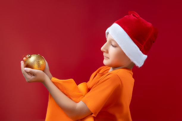 一个在红色背景上戴圣诞帽的男孩图片下载