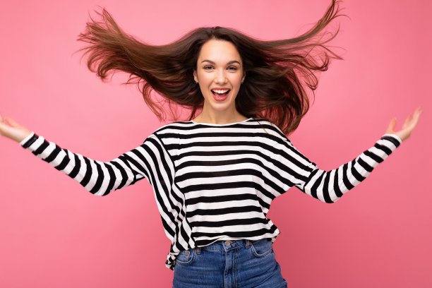 照片肖像年轻美丽的微笑嬉皮士黑发女人在时尚的套衫。性感无忧无虑的女性在工作室的粉红色墙壁附近摆着孤立的空空间。自然妆容的正面模特图片下载