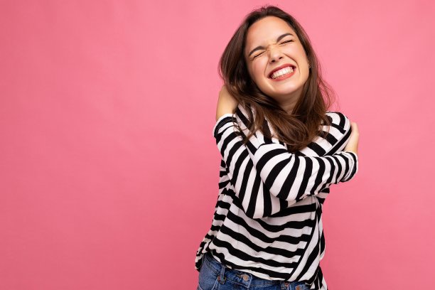 照片肖像年轻美丽的微笑嬉皮士黑发女人在时尚的套衫。性感无忧无虑的女性在工作室的粉红色墙壁附近摆着孤立的空空间。自然妆容的正面模特图片下载