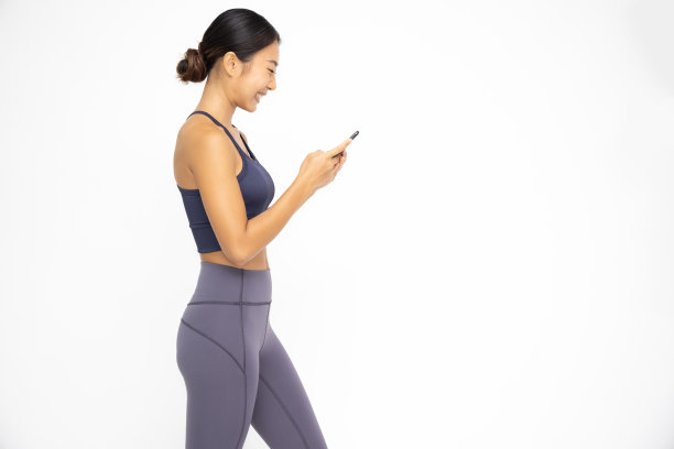 快乐年轻的亚洲运动妇女使用手机，打字短信，聊天的通信应用程序隔离在白色的背景图片下载
