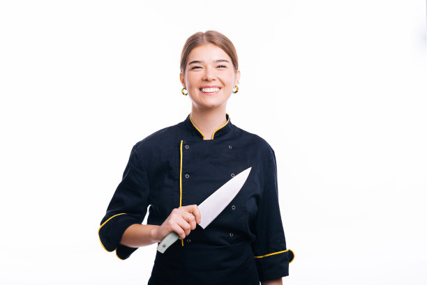 漂亮的女厨师拿着刀站在镜头前微笑。图片下载