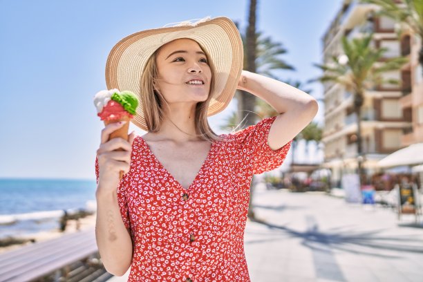年轻的中国女孩微笑着快乐地吃着冰淇淋在长廊。图片下载